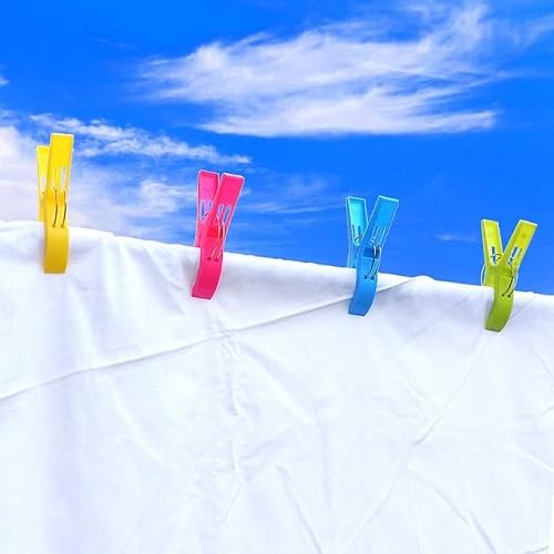 Colorful XXL plastic clothespins gripping white fabric outdoors under a blue sky, designed for beach towels, sunbeds, and laundry.