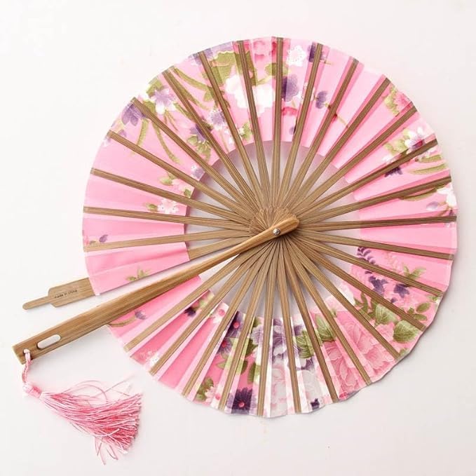 Traditional round folding hand fan by 7AGAT in vibrant red with floral pattern, displayed on a decorative wooden stand.