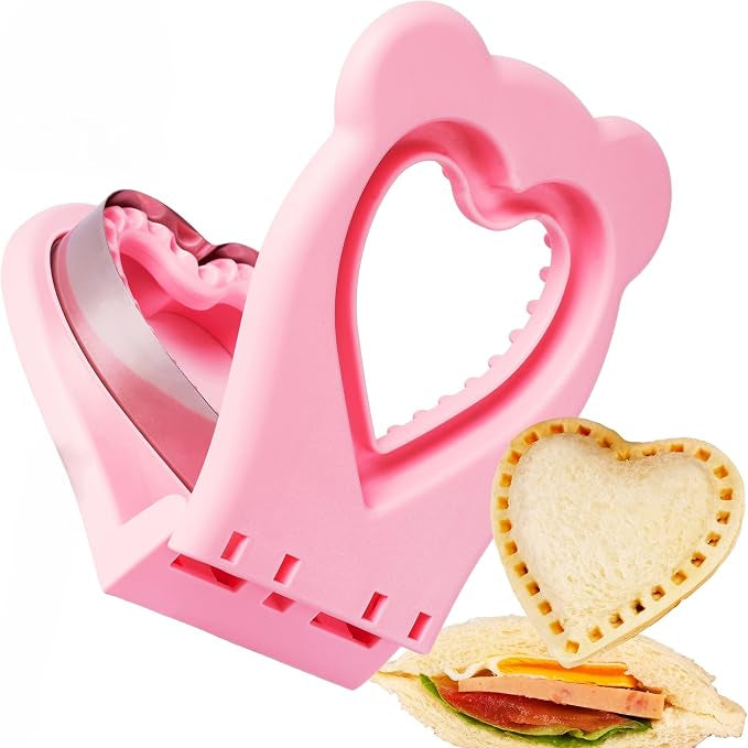 Pink heart-shaped sandwich maker or press tool with a metal inner blade, shown open on a white background, alongside a heart-shaped pressed sandwich.