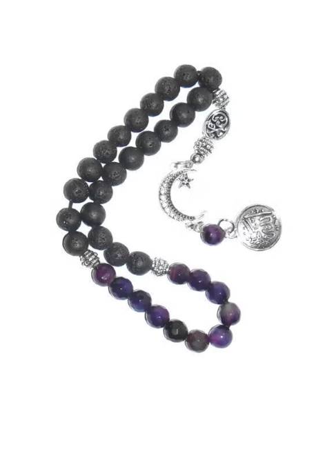 A beaded necklace featuring dark gray lava stone beads and purple amethyst beads, accented with silver-toned metal charms including a crescent moon, star, and a round engraved medallion.
