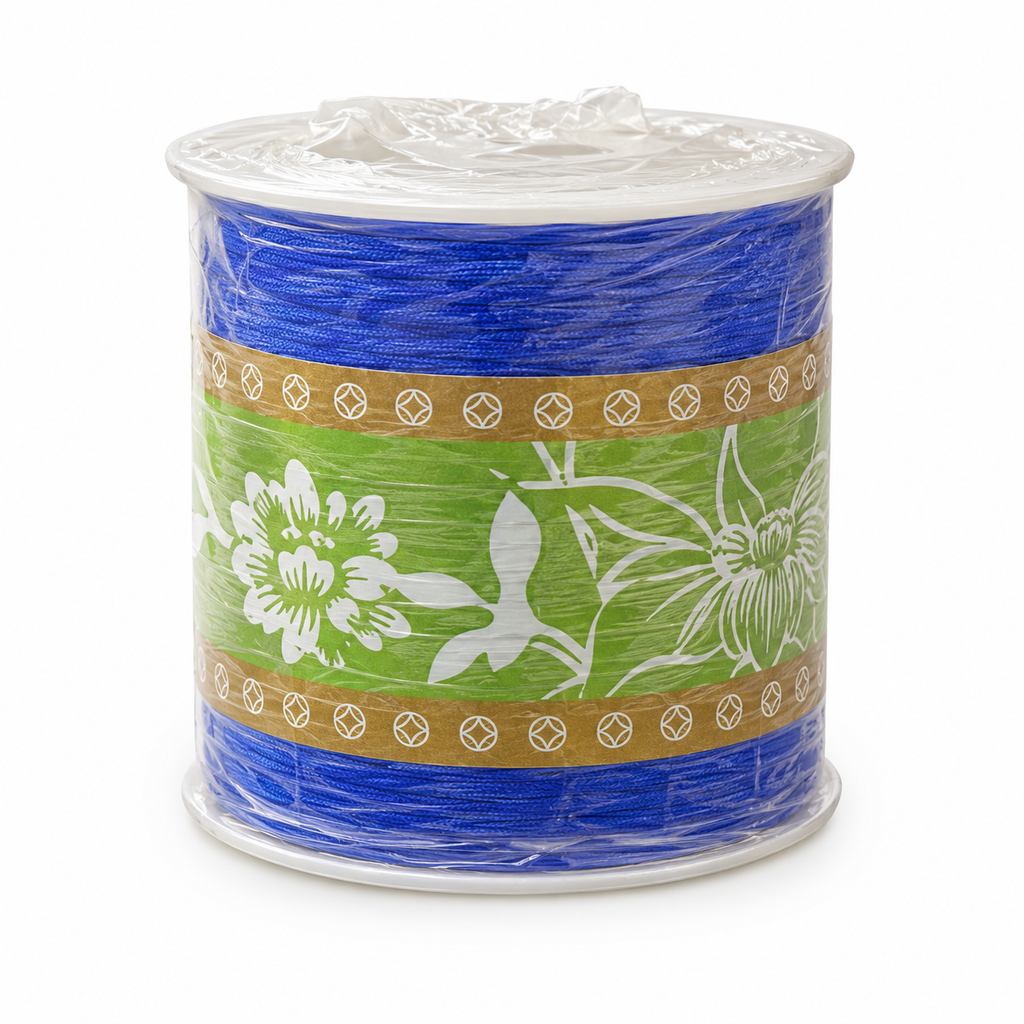 A spool of royal blue ribbon with a green and white floral patterned paper band around the middle, wrapped in clear plastic on a white background.