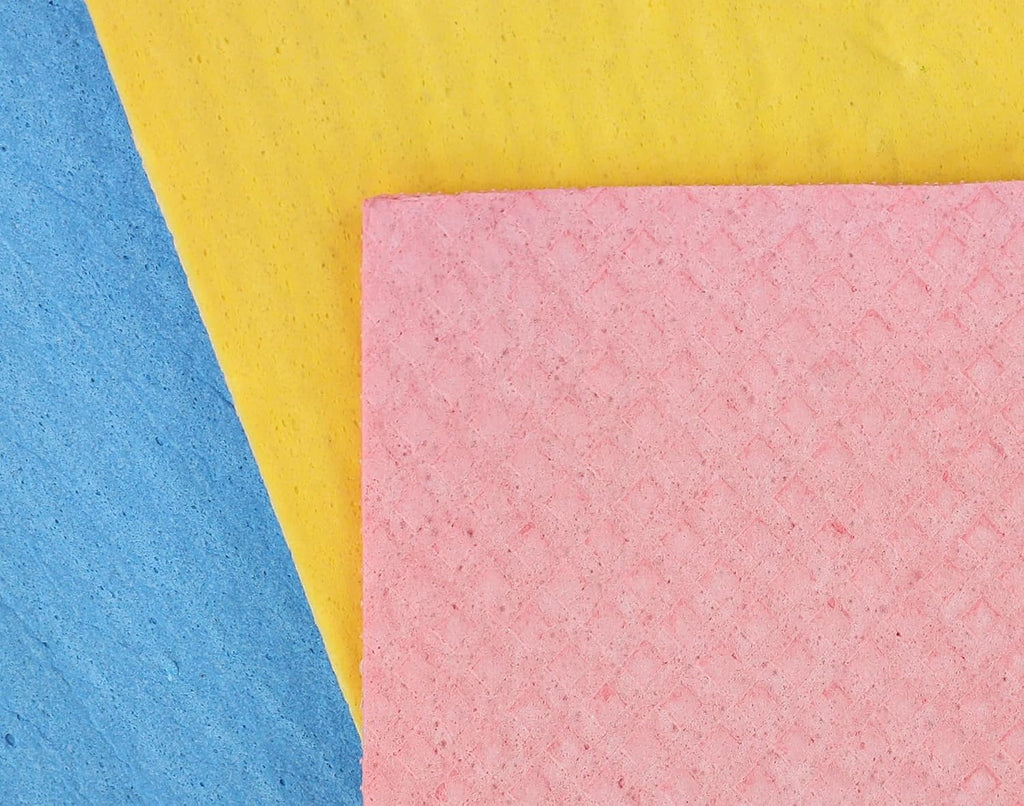 Three textured square paper sheets in pink, yellow, and blue arranged diagonally on a white background.