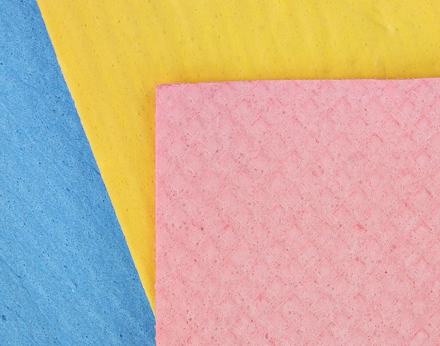 Three textured square paper sheets in pink, yellow, and blue arranged diagonally on a white background.