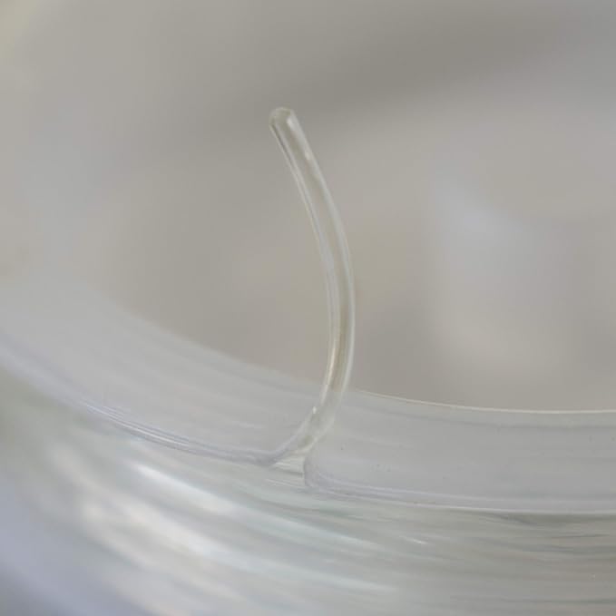 A close-up of a semi-transparent clear plastic or silicone looped tube resting on a soft, out-of-focus light gray background.
