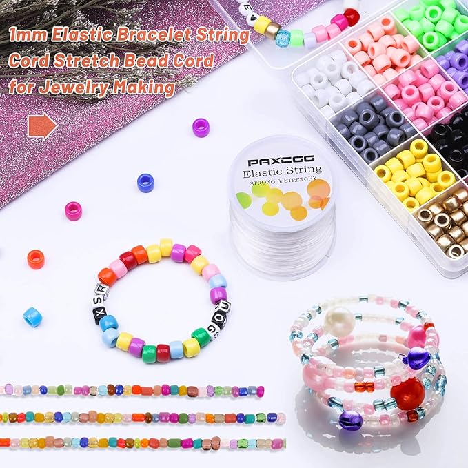 Colorful beaded bracelets and a spool of elastic string on a white background
