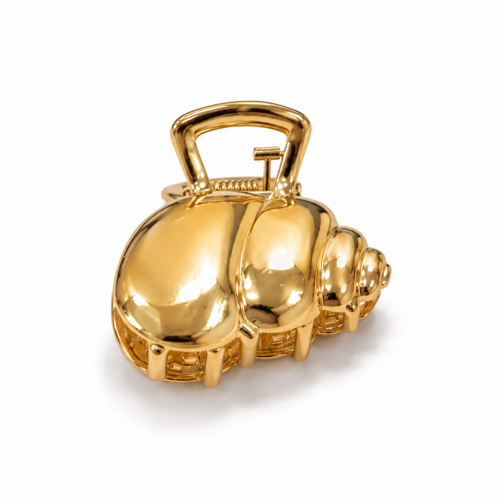 A shiny gold-toned shell-shaped accessory with a loop handle, photographed on a clean white background.