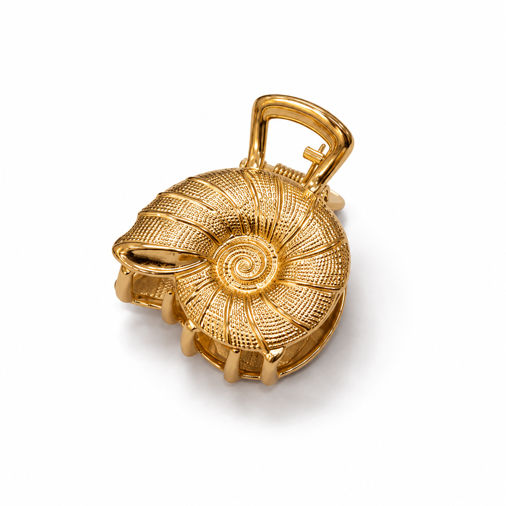 A gold-colored hair claw clip designed in the shape of a nautilus shell, featuring a textured spiral center and a hinged clasp mechanism at the top, shown on a clean white background.