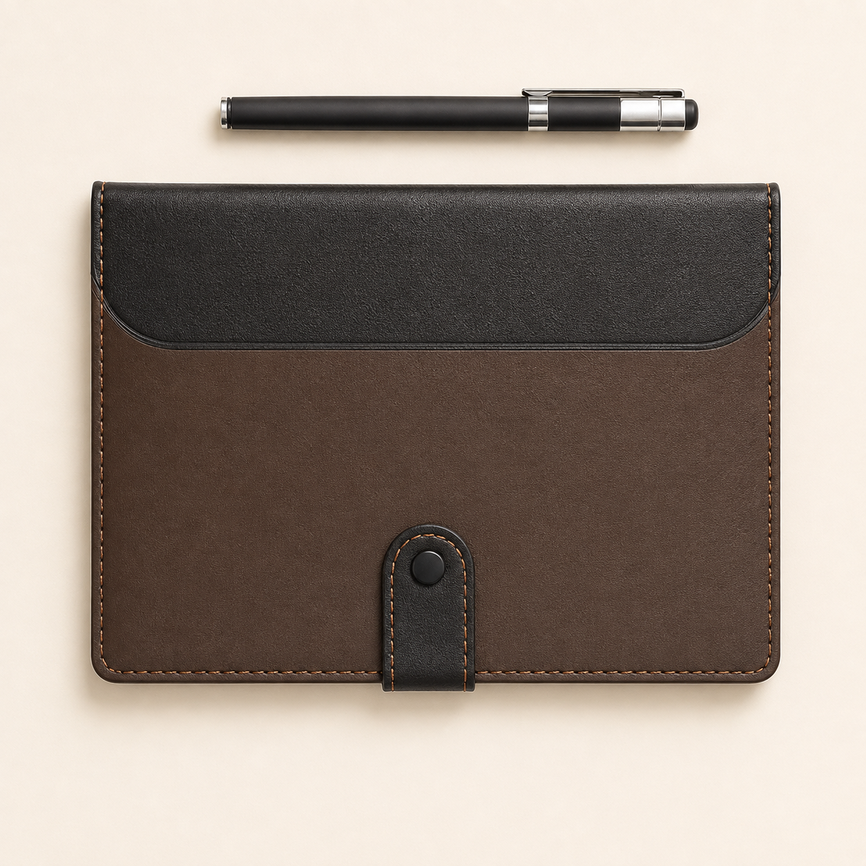 A brown and black leather card holder or document sleeve with a snap tab closure, shown flat on a light beige background with a black pen placed above it.