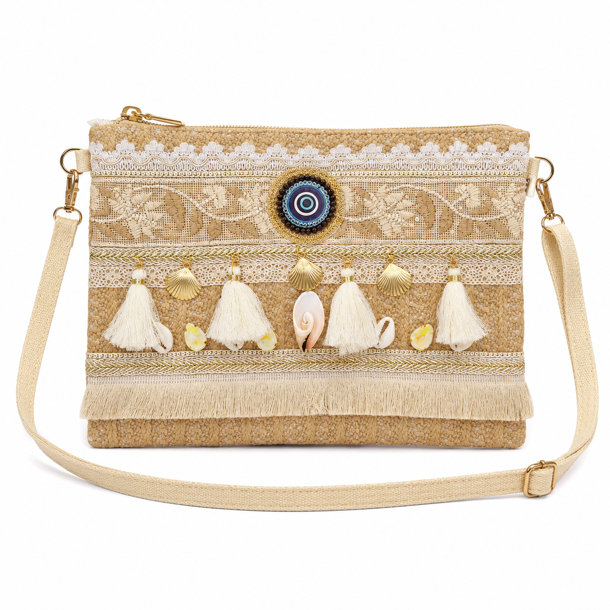 A bohemian-style woven clutch bag in beige and cream, decorated with white lace, tassel charms, seashells, a blue and white evil eye emblem, and gold-tone hardware, shown on a white background.
