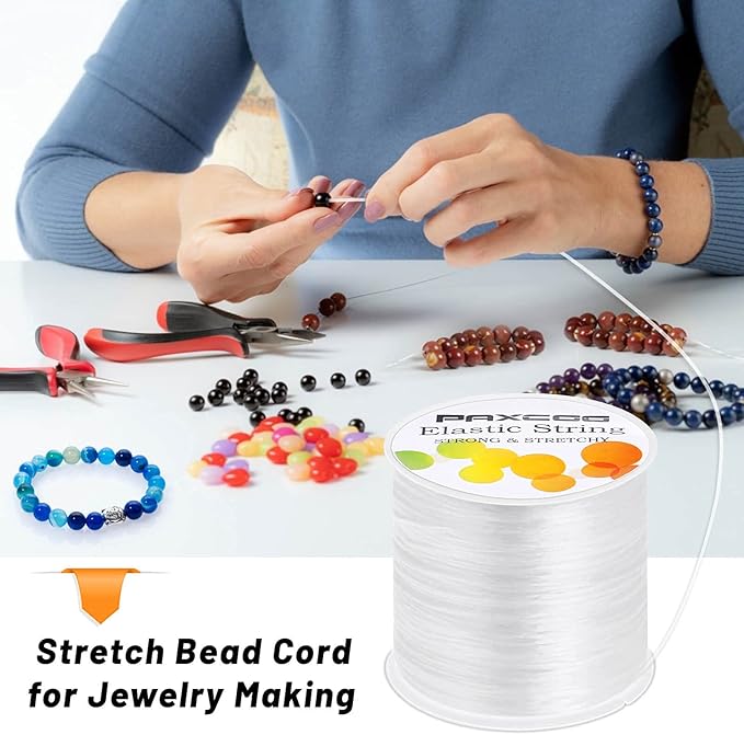 Person making jewelry with beads and stretch bead cord, surrounded by tools on a white surface.