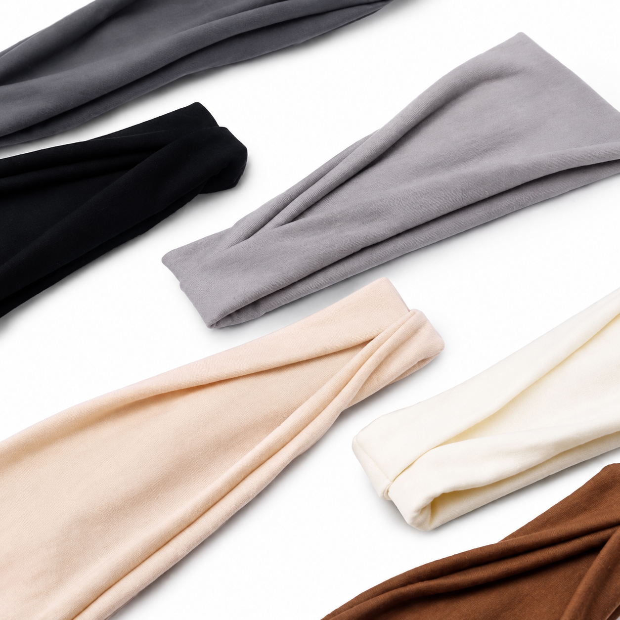 Soft fabric headbands بألوان neutral مرتبة بشكل أنيق على خلفية بيضاء clean، مع modern minimalist style مناسب لعرض منتجات fashion & accessories بطريقة ناعمة وعصرية.
