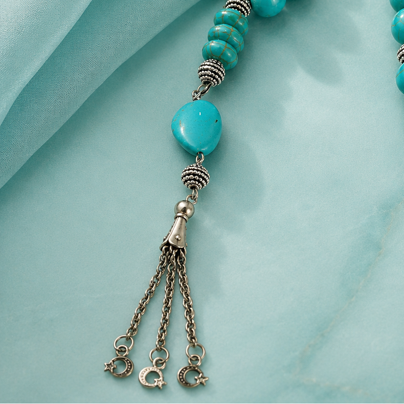 Turquoise beaded necklace with silver accents on a light blue fabric background