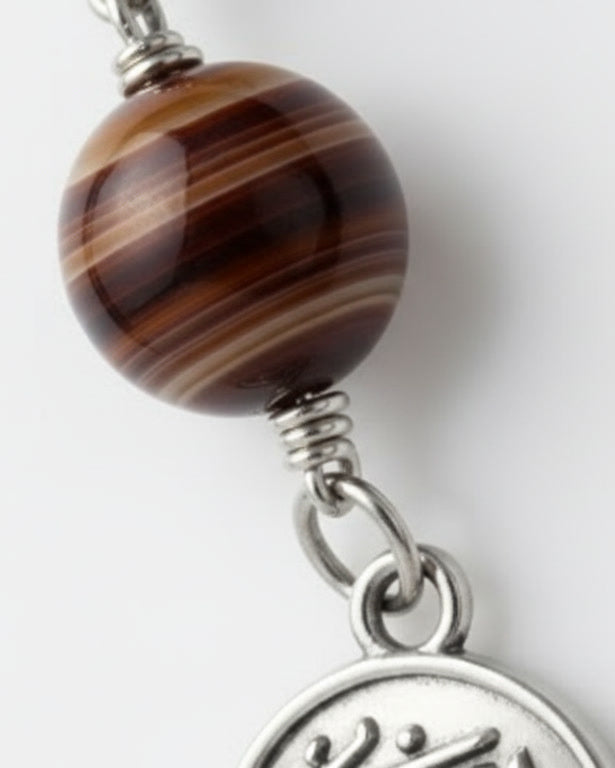 Jewelry with a large brown bead and a silver charm on a white background